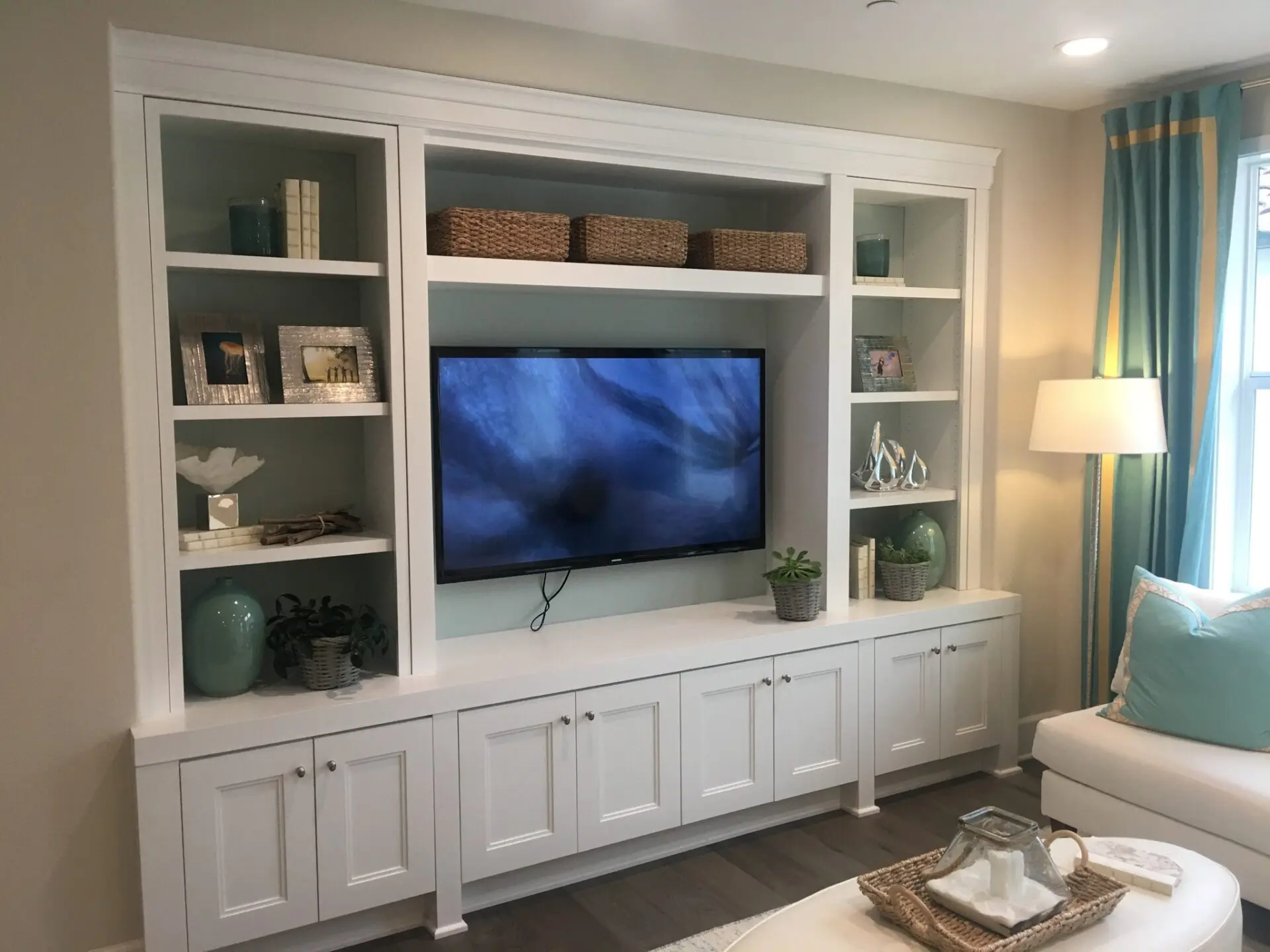 A living room with white cabinets and a flat screen tv.