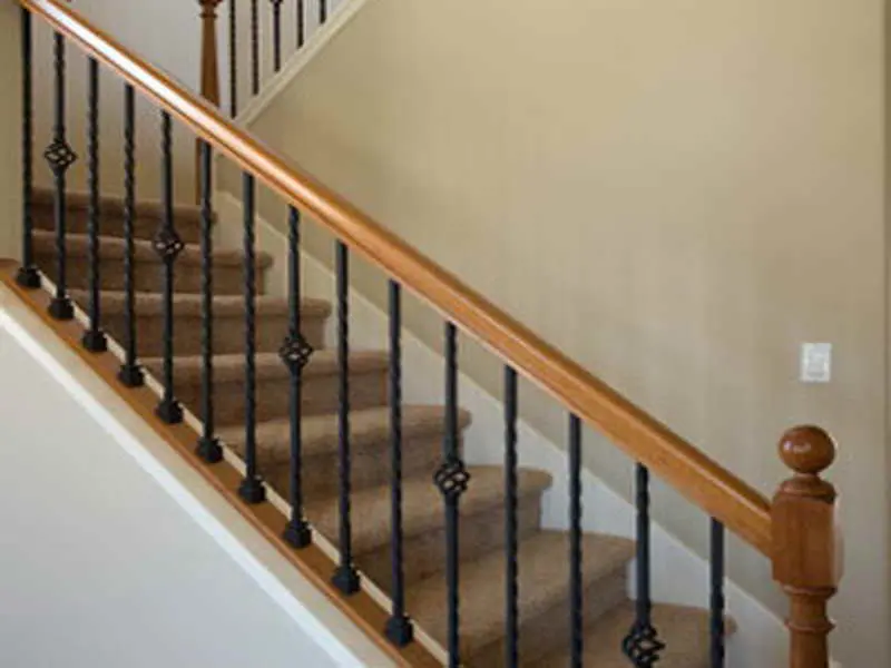 A staircase with wooden handrails and metal spindles.