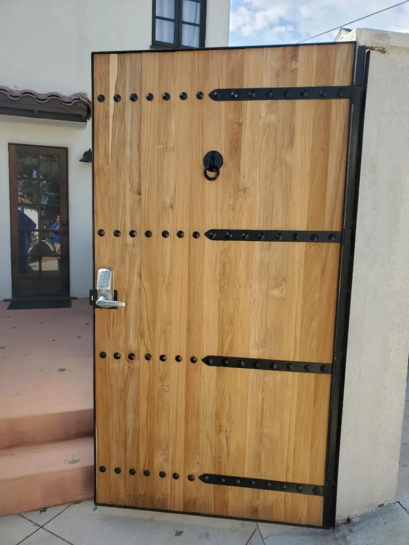 A wooden door with metal hardware and black trim.