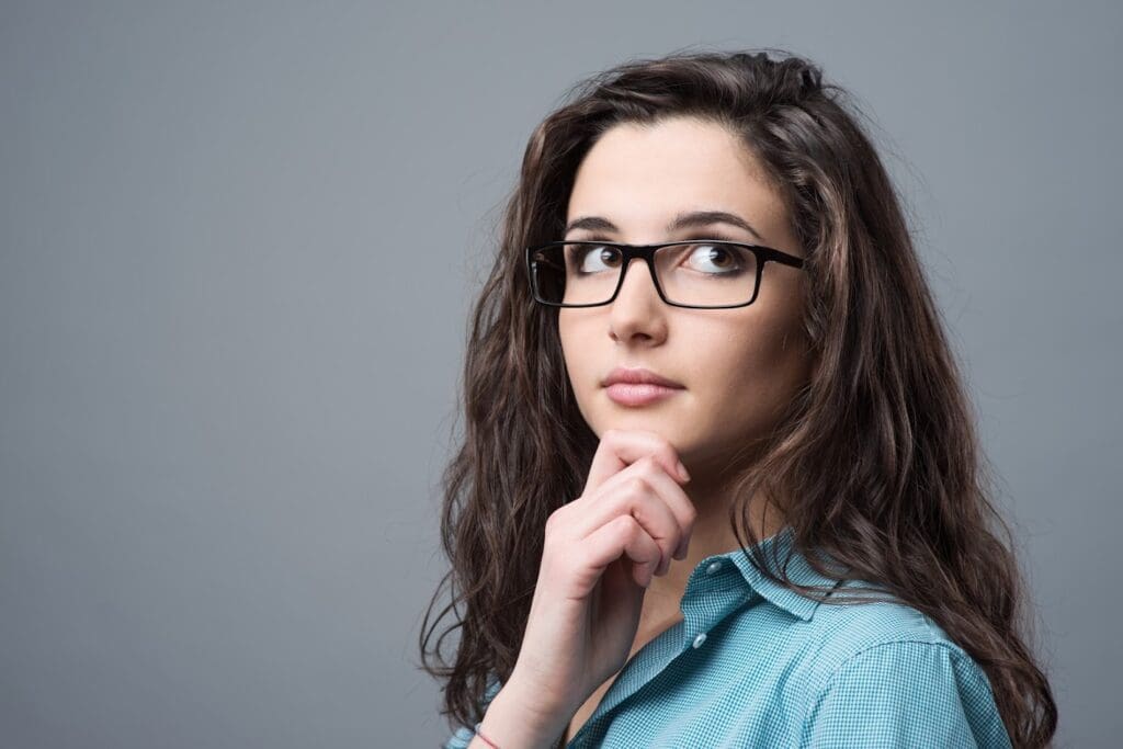 A woman with glasses is looking up at the sky.