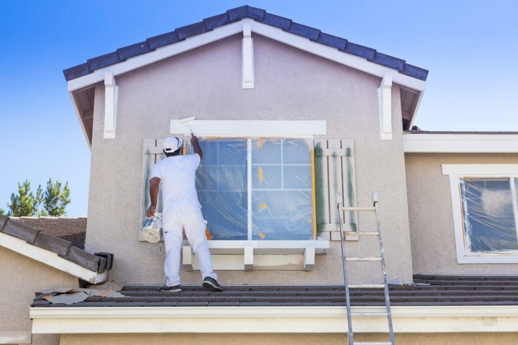 A man painting the outside of a house.